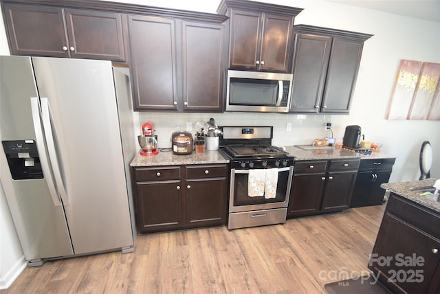 kitchen featuring appliances with stainless steel finishes, dark brown cabinetry, and light hardwood / wood-style floors