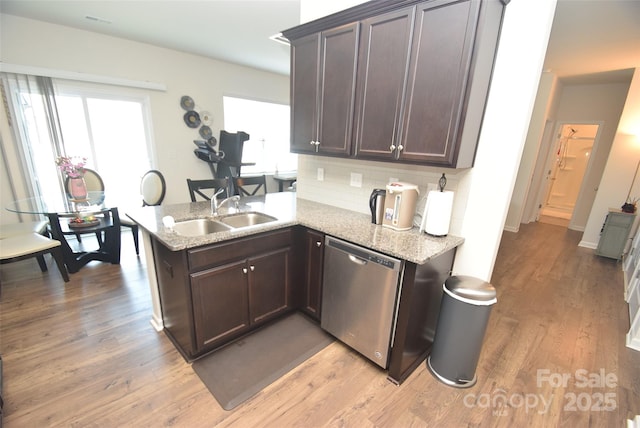 kitchen with dishwasher, sink, backsplash, dark brown cabinetry, and light hardwood / wood-style flooring