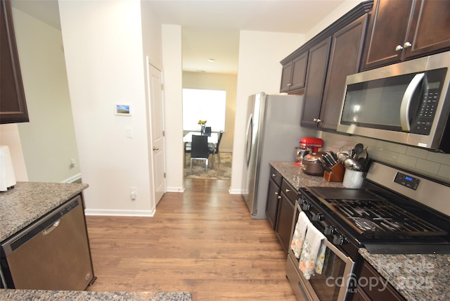 kitchen featuring light hardwood / wood-style flooring, dark brown cabinets, light stone countertops, and appliances with stainless steel finishes