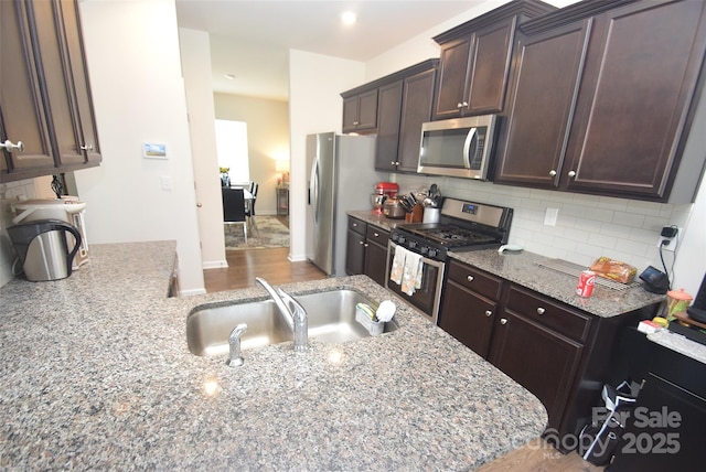 kitchen with light stone counters, sink, decorative backsplash, and appliances with stainless steel finishes