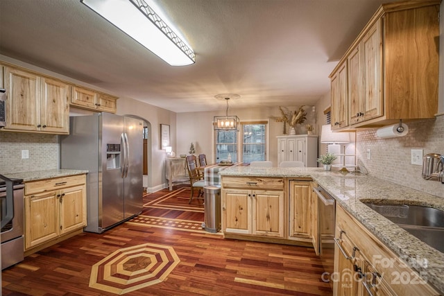 kitchen with dark wood-type flooring, sink, hanging light fixtures, appliances with stainless steel finishes, and light stone countertops