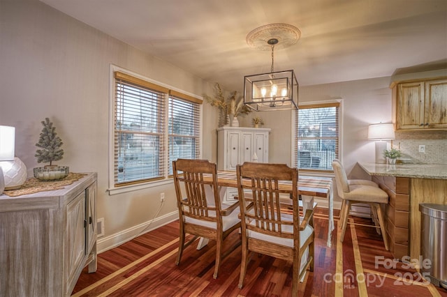 dining area with dark hardwood / wood-style floors and a notable chandelier