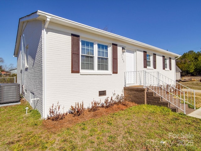 view of front of house with central AC unit and a front lawn