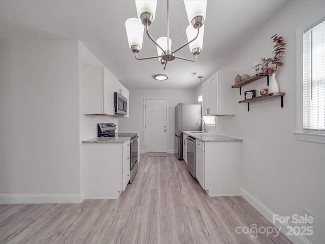 kitchen featuring sink, appliances with stainless steel finishes, light hardwood / wood-style floors, white cabinets, and a chandelier