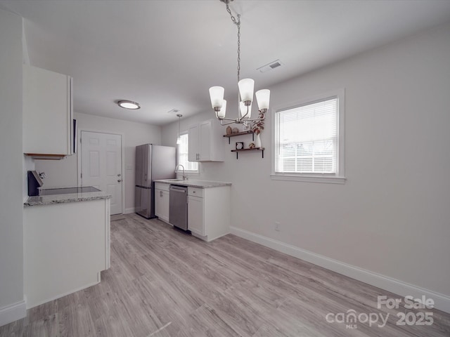 kitchen with an inviting chandelier, pendant lighting, stainless steel appliances, light hardwood / wood-style floors, and white cabinets