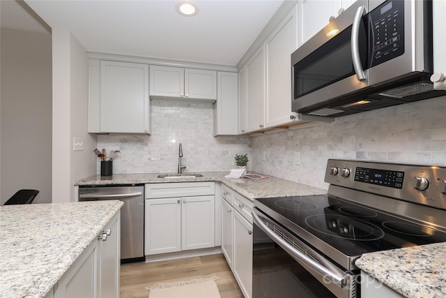 kitchen featuring sink, light stone countertops, white cabinets, and appliances with stainless steel finishes