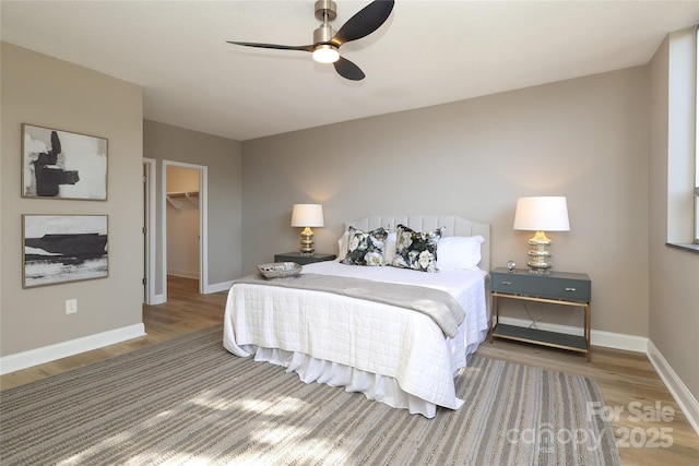 bedroom featuring hardwood / wood-style floors, a walk in closet, a closet, and ceiling fan