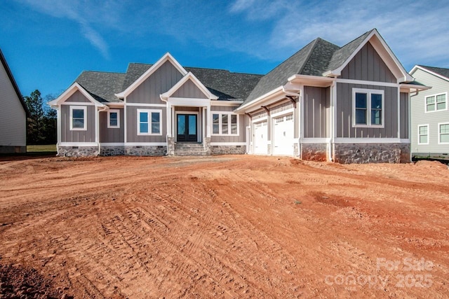 craftsman-style home with an attached garage, board and batten siding, and roof with shingles