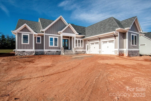 craftsman inspired home with a shingled roof, dirt driveway, crawl space, an attached garage, and board and batten siding