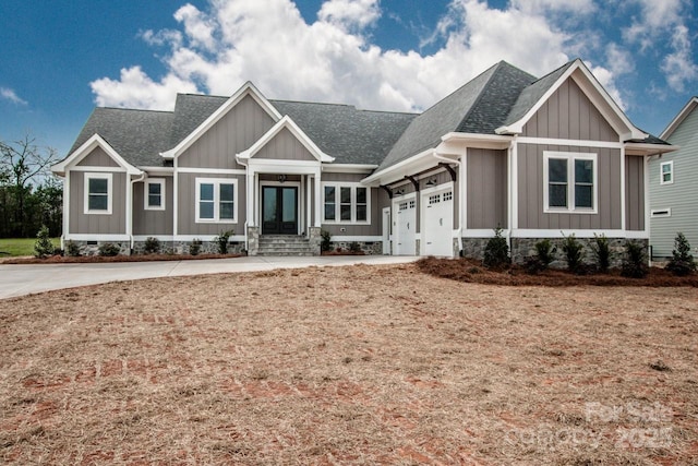 craftsman inspired home featuring an attached garage, a shingled roof, board and batten siding, crawl space, and driveway