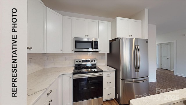 kitchen featuring light stone counters, white cabinetry, appliances with stainless steel finishes, dark hardwood / wood-style floors, and backsplash