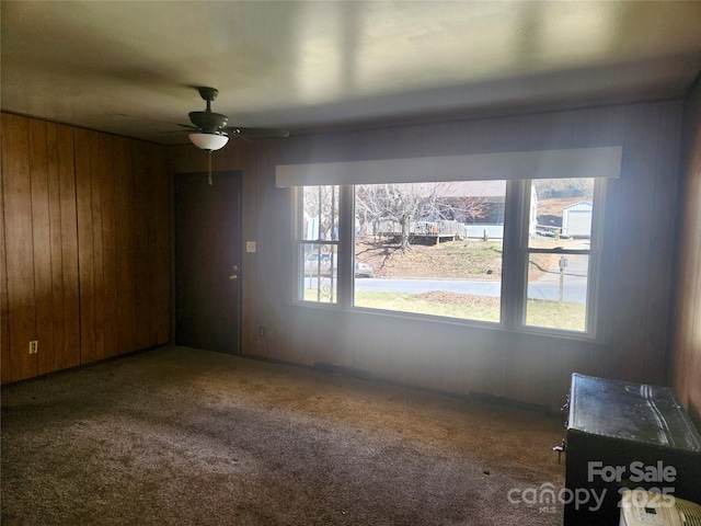 interior space featuring wood walls and a ceiling fan