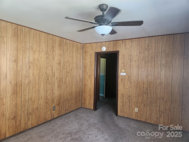 carpeted empty room with a ceiling fan and wooden walls