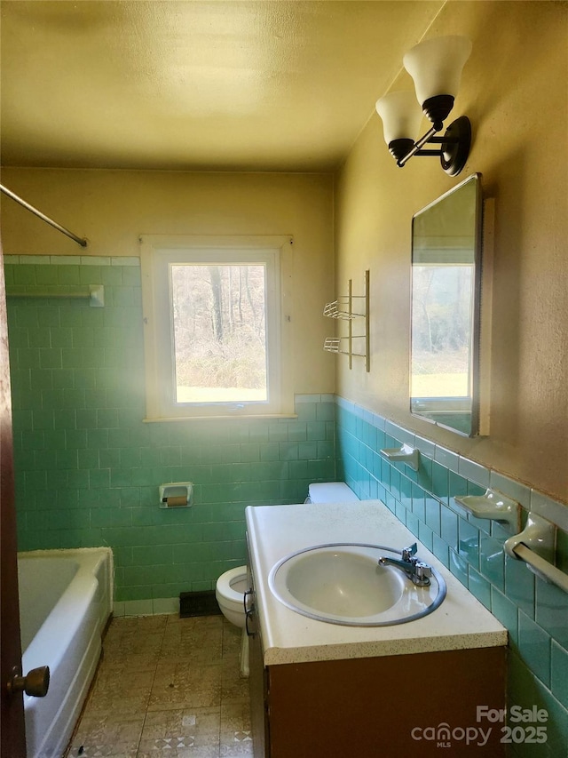 bathroom with a wainscoted wall, tile walls, toilet, a textured ceiling, and vanity