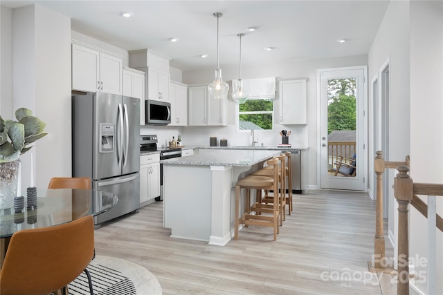 kitchen with pendant lighting, white cabinetry, stainless steel appliances, and a kitchen island