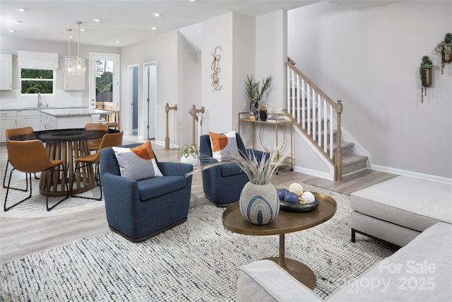 living room with sink, a chandelier, and light wood-type flooring