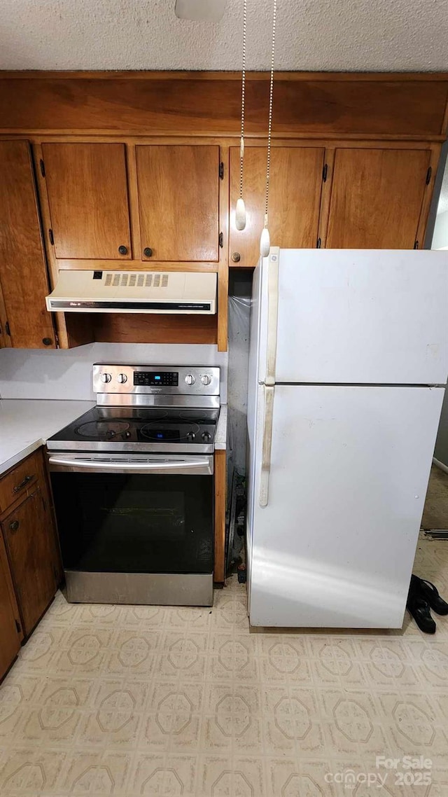 kitchen featuring stainless steel electric range, white fridge, and a textured ceiling