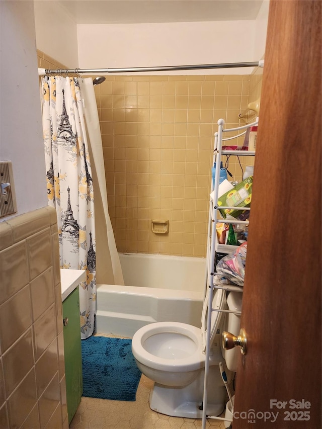 full bathroom with toilet, tile walls, vanity, shower / bath combo with shower curtain, and tile patterned flooring