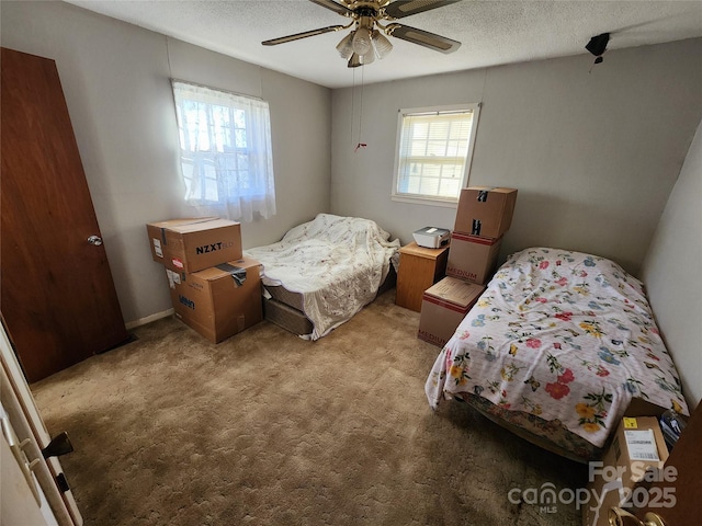 carpeted bedroom featuring ceiling fan and a textured ceiling