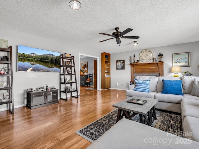 living room with hardwood / wood-style flooring, ceiling fan, and a textured ceiling