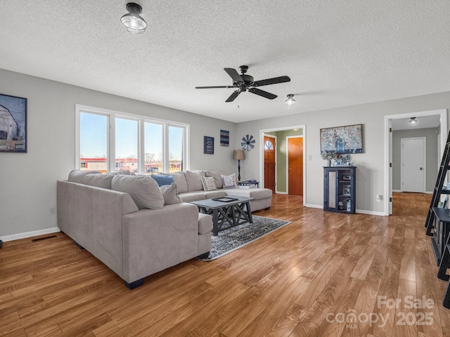 living room featuring wood-type flooring, ceiling fan, and a textured ceiling