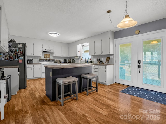 kitchen with sink, white cabinets, a kitchen island, white electric stove, and french doors