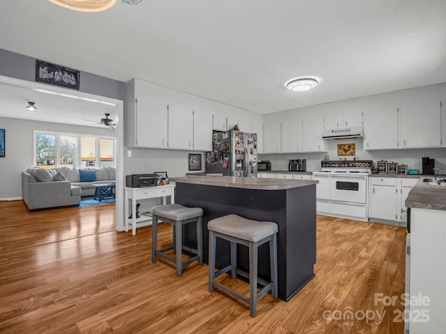 kitchen with white cabinetry, stainless steel fridge with ice dispenser, a kitchen breakfast bar, a kitchen island, and range with two ovens