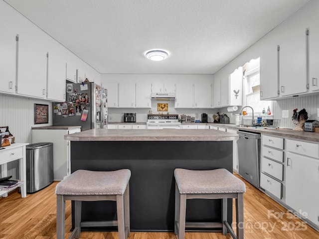 kitchen with a kitchen island, a breakfast bar, white cabinets, and appliances with stainless steel finishes