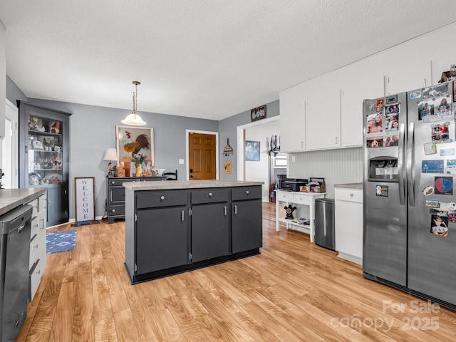 kitchen featuring decorative light fixtures, white cabinetry, dishwasher, stainless steel fridge, and light wood-type flooring