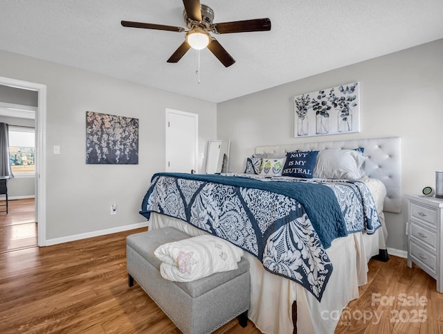 bedroom featuring ceiling fan, hardwood / wood-style floors, and a textured ceiling