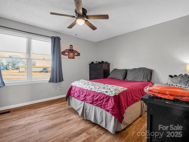 bedroom with ceiling fan, light hardwood / wood-style floors, and a textured ceiling