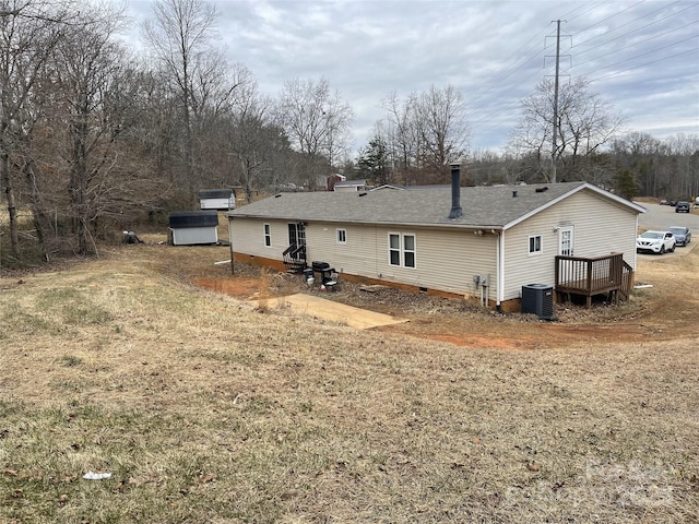 back of property with a wooden deck, central AC unit, and a lawn