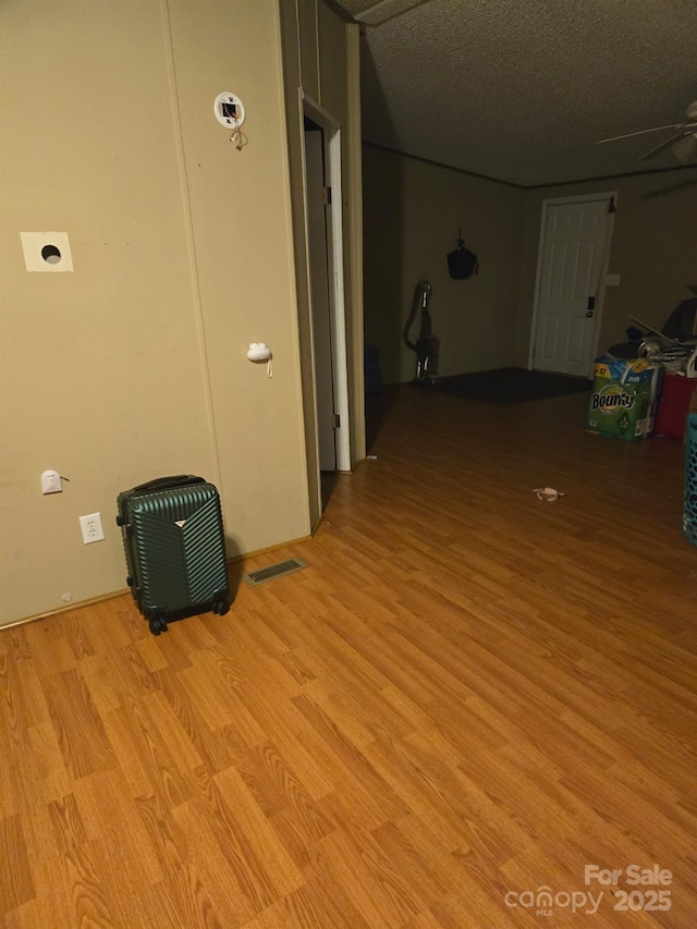 hall with a textured ceiling and light hardwood / wood-style floors