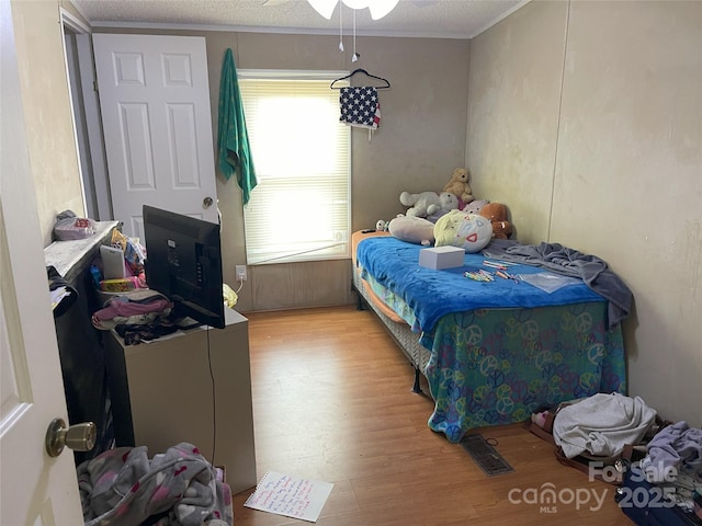 bedroom featuring ornamental molding, a textured ceiling, and light hardwood / wood-style flooring