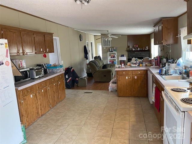 kitchen featuring sink, white appliances, light tile patterned floors, ceiling fan, and kitchen peninsula