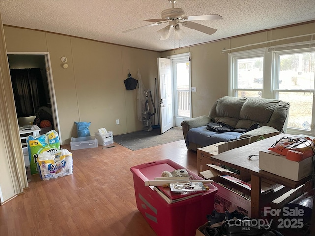 living room featuring lofted ceiling, crown molding, a textured ceiling, light wood-type flooring, and ceiling fan