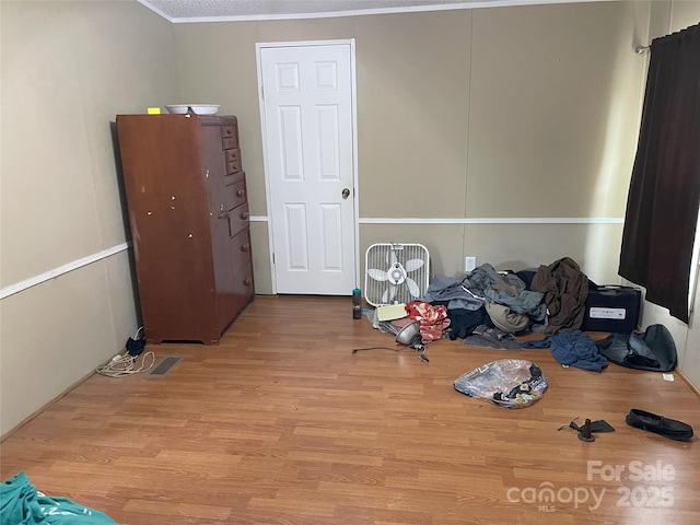 misc room featuring crown molding, a textured ceiling, and light wood-type flooring