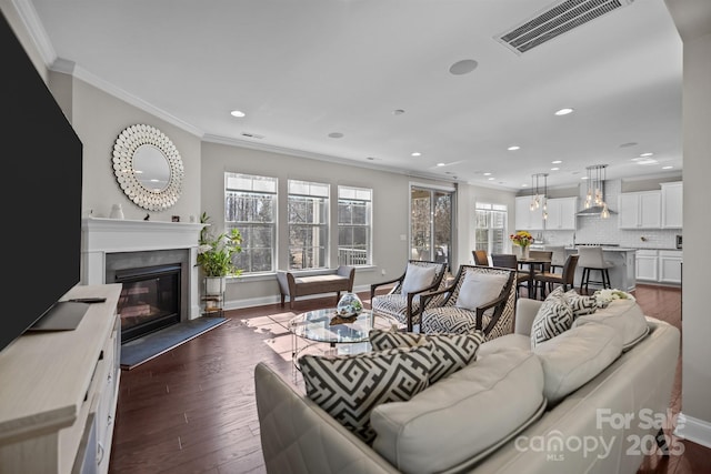 living room with crown molding, dark wood-type flooring, and a fireplace