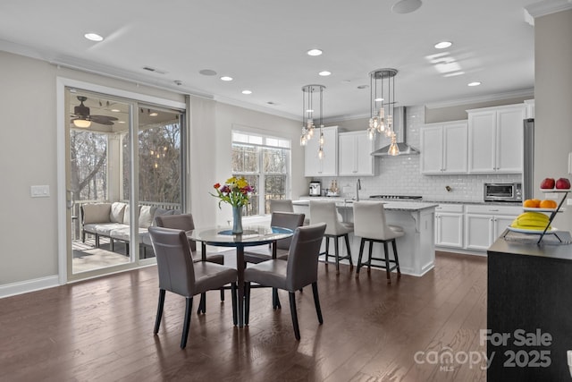 dining space with crown molding, dark wood-type flooring, and ceiling fan