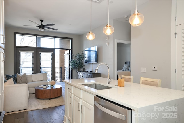 kitchen featuring an island with sink, sink, white cabinets, hanging light fixtures, and stainless steel dishwasher