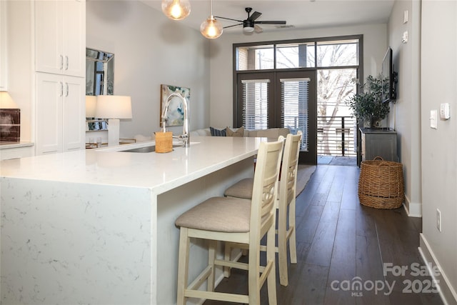 kitchen with decorative light fixtures, sink, white cabinets, dark wood-type flooring, and french doors