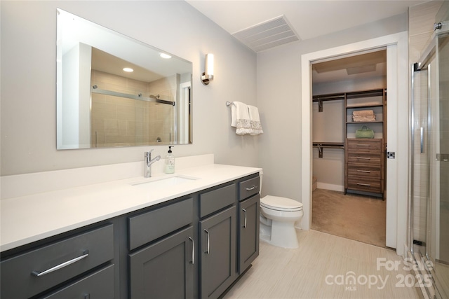 bathroom featuring vanity, toilet, and a shower with shower door