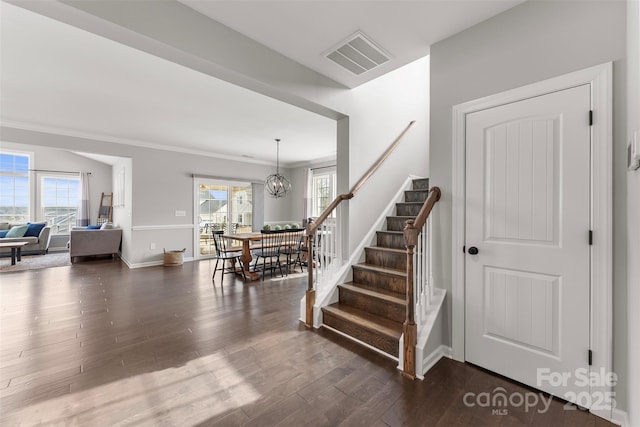 stairs with a wealth of natural light, visible vents, a chandelier, and wood finished floors