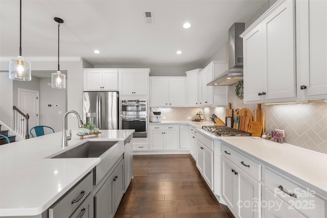 kitchen featuring stainless steel appliances, wall chimney range hood, light countertops, and white cabinets