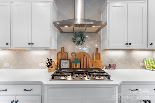 kitchen featuring wall chimney exhaust hood, light countertops, white cabinetry, and stainless steel gas stovetop