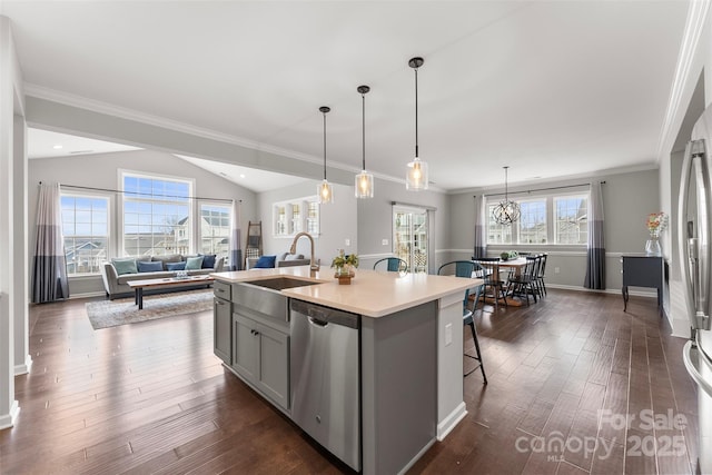 kitchen with stainless steel appliances, a sink, open floor plan, light countertops, and an island with sink