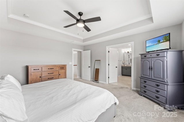 bedroom with baseboards, a tray ceiling, ensuite bath, and light colored carpet