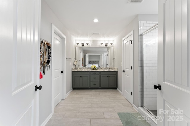 full bathroom with a sink, a shower stall, and double vanity