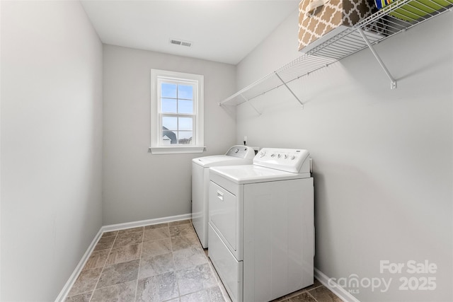 laundry area with laundry area, washing machine and clothes dryer, visible vents, and baseboards