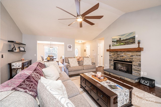 living room featuring a stone fireplace, vaulted ceiling, ceiling fan, and light wood-type flooring